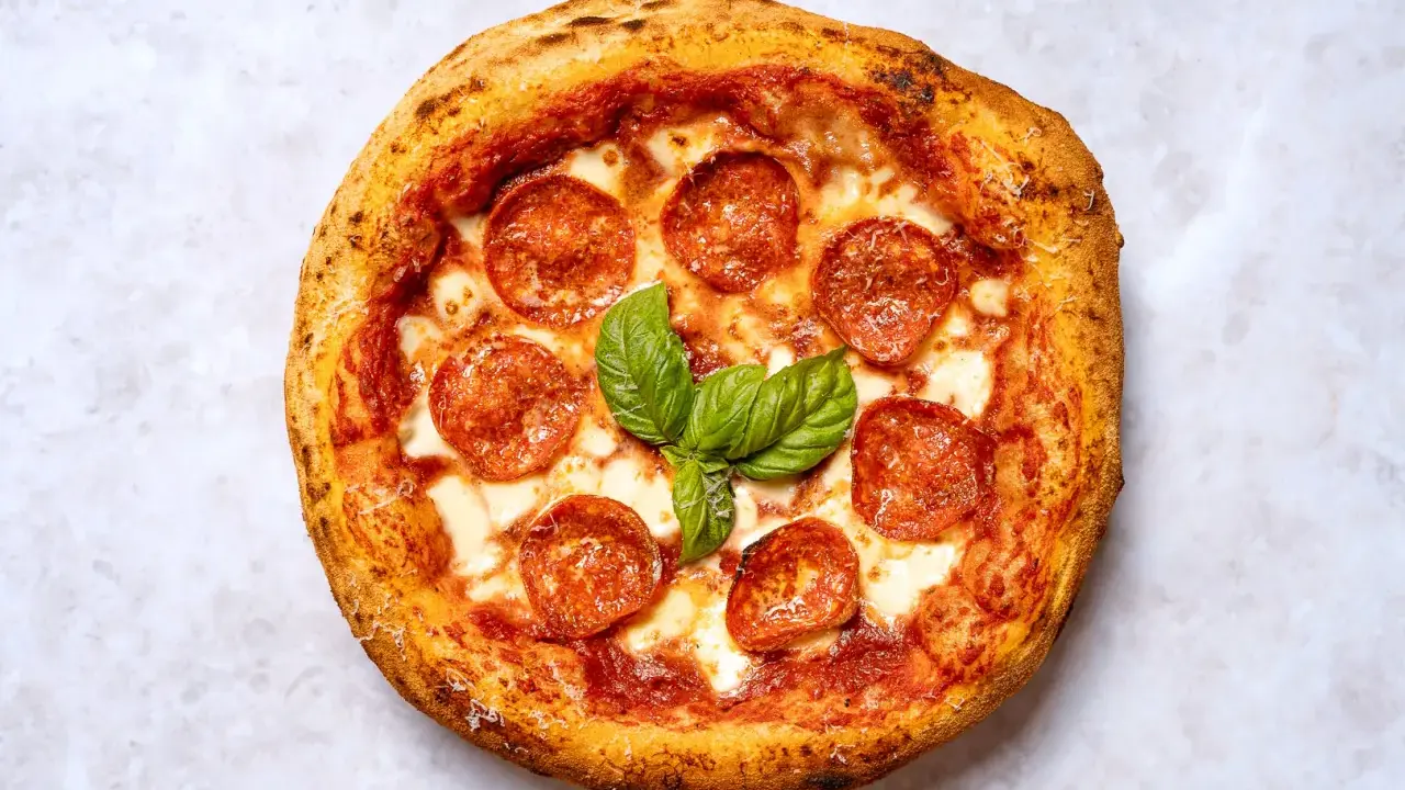 Eine köstliche New York Style Pizza mit Salami und frischem Basilikum, bereit zum Genießen.
