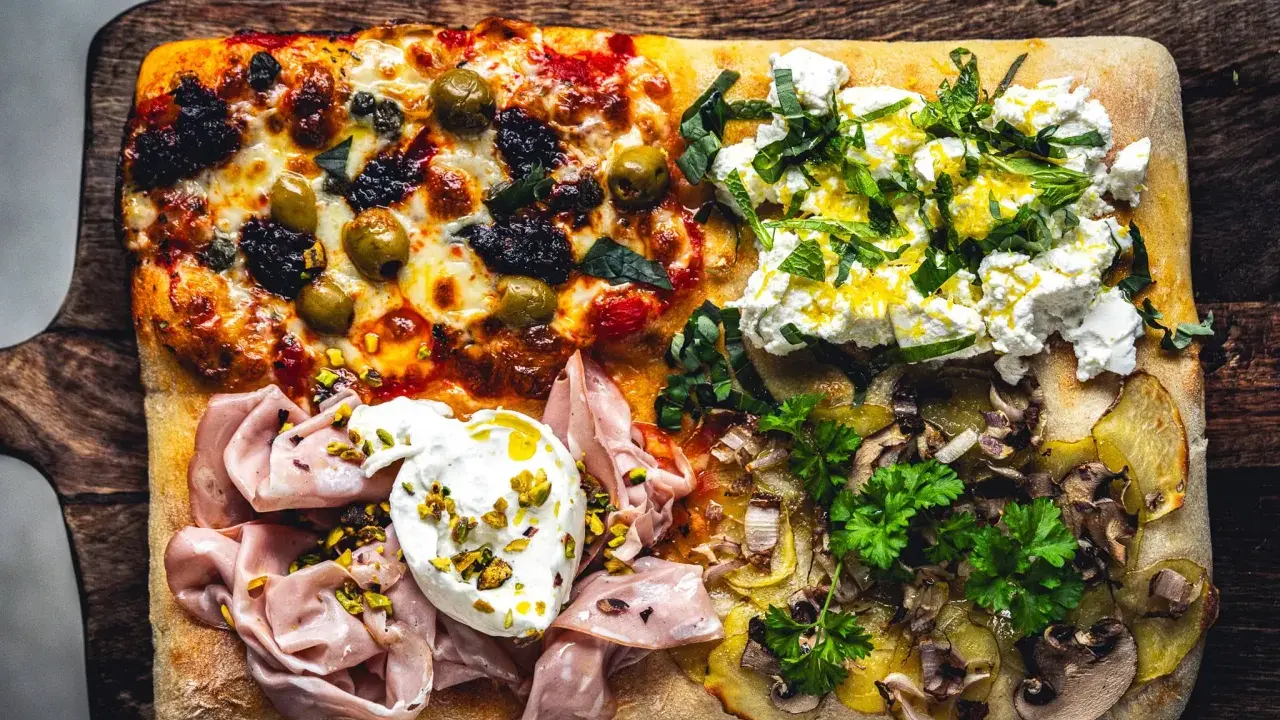 Vier verschiedene Beläge auf einer rechteckigen Pizza in Teglia: Oliven & Tomaten, Ricotta & Kräuter, Mortadella & Burrata, Kartoffeln & Pilze.