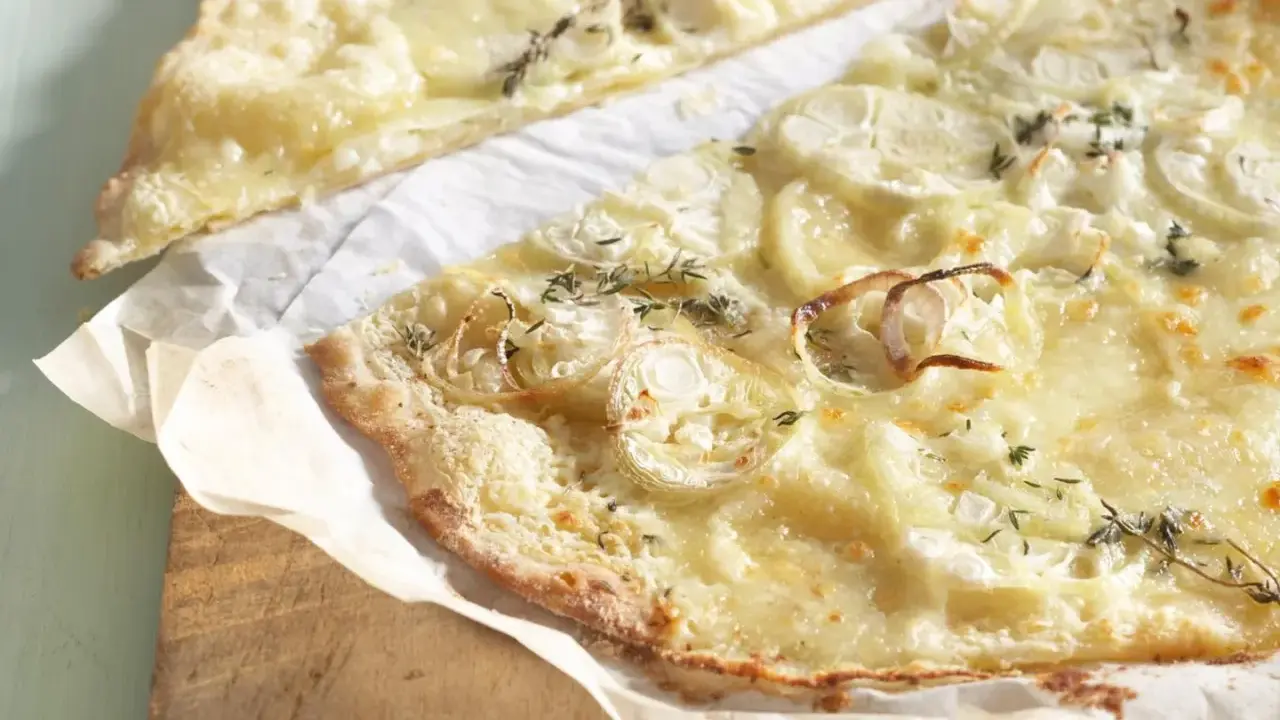 Dünne, knusprige knoblauch pizza mit geschmolzenem Käse und Zwiebelringen, garniert mit frischen Kräutern.