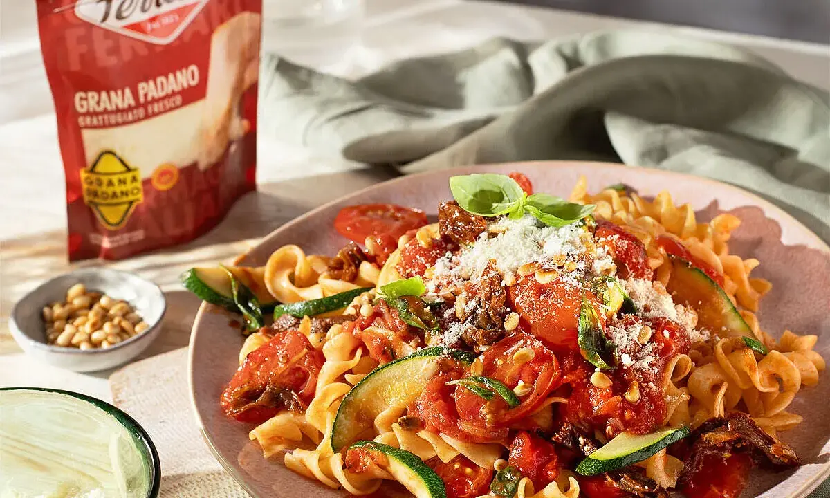 Pasta mit Tomaten, Zucchini und Pinienkernen, bestreut mit Grana Padano. Diese Parmesan-Sorten verfeinern jedes Gericht.