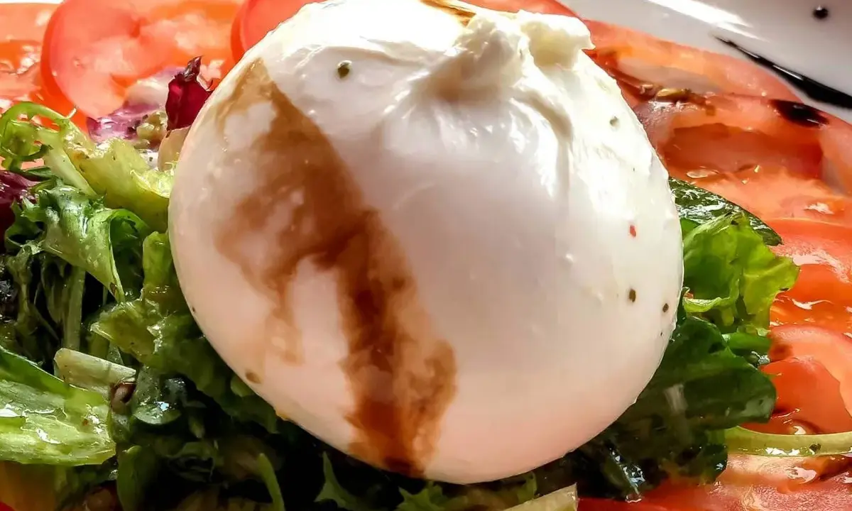 Cremige Burrata auf Tomaten und Salat, ein einfaches Gericht, das sich perfekt für Burrata Rezepte eignet.