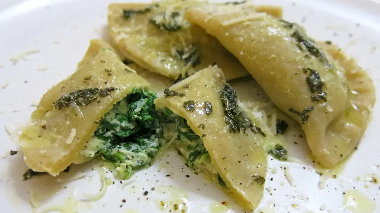 Mezzelune spinaci, gefüllt mit cremigem Spinat und Ricotta, beträufelt mit Olivenöl und bestreut mit Parmesan.