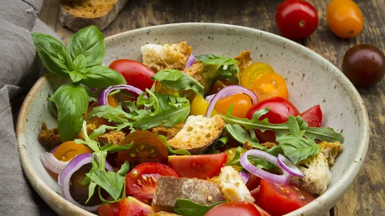 Bunter Tomatensalat mit Brotstücken, Zwiebeln und Basilikum, verfeinert mit einem Hauch Balsamico Dressing.