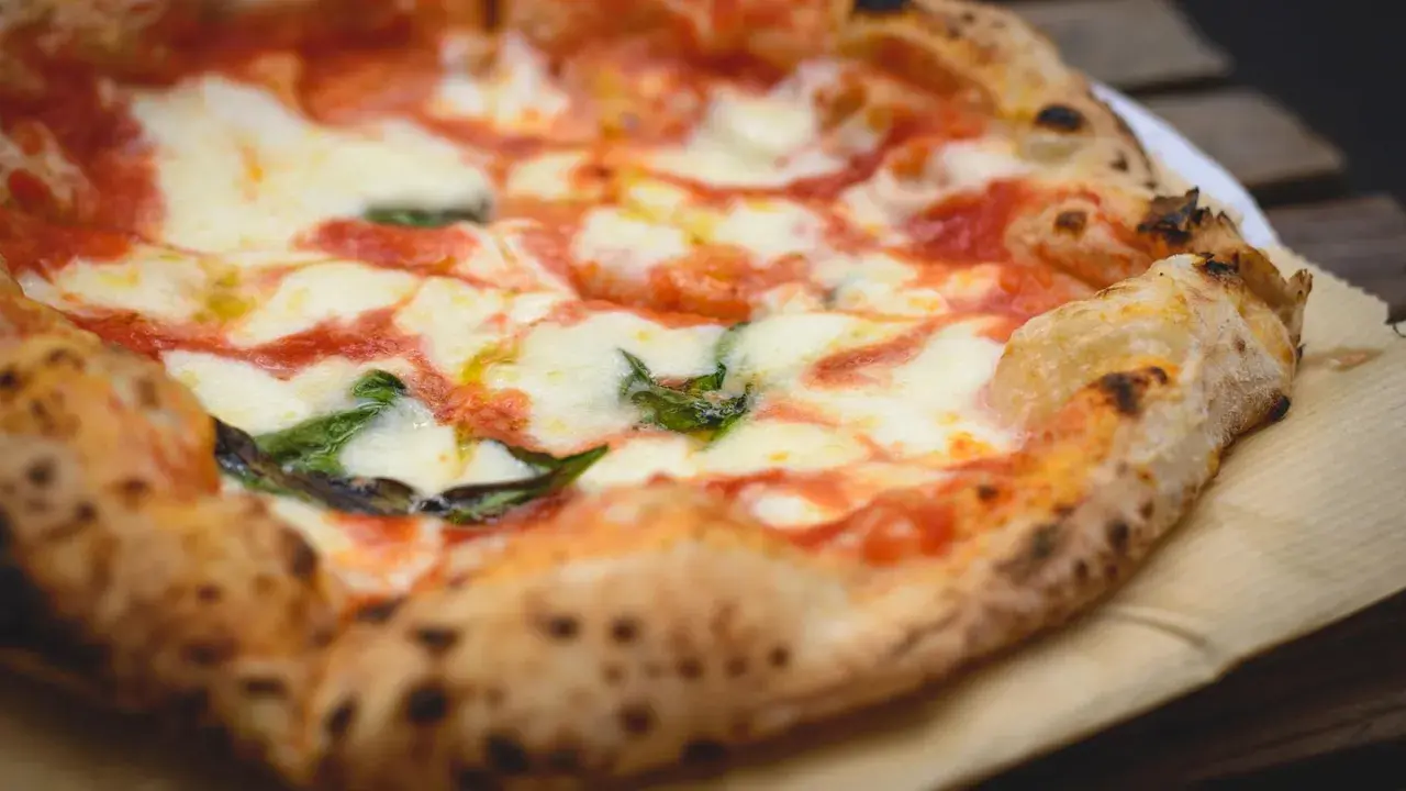Ein frisch gebackener, italienischer Pizzateig mit geschmolzenem Mozzarella, Tomatensauce und Basilikum.