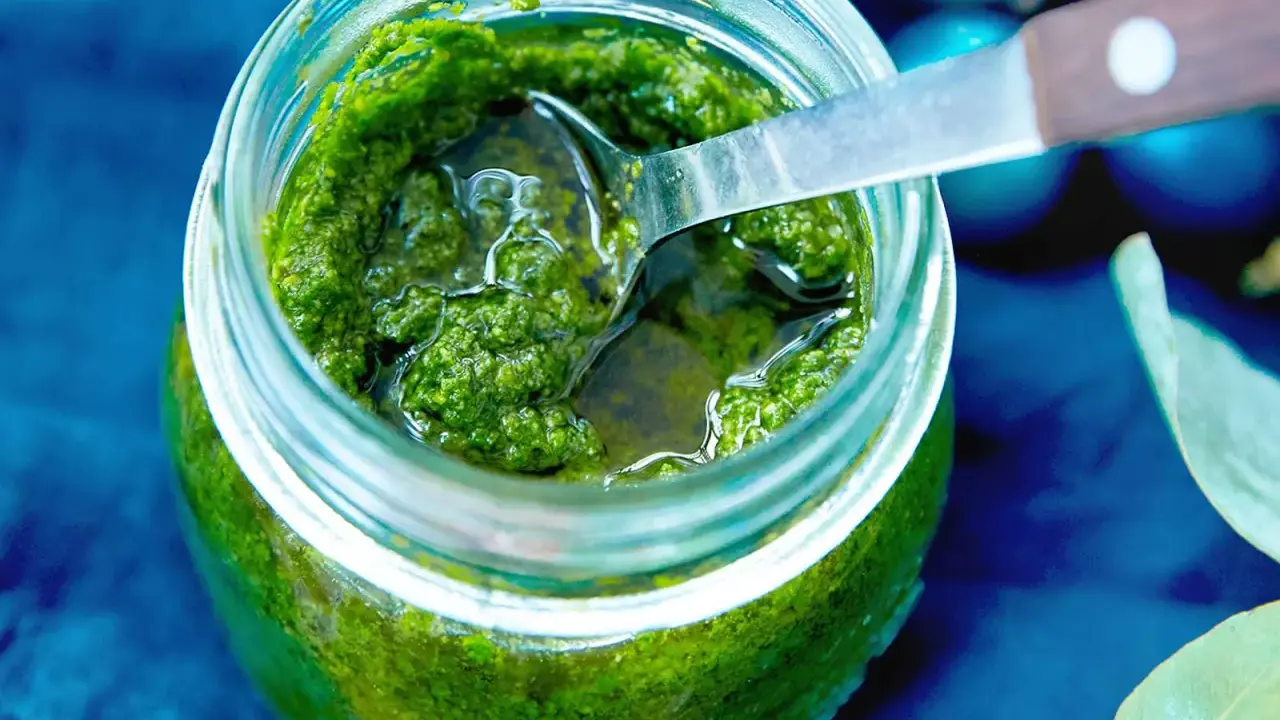 Frisches Rucola Pesto in einem Glas, bereit zum Genießen. Eine Löffelspitze ragt heraus.