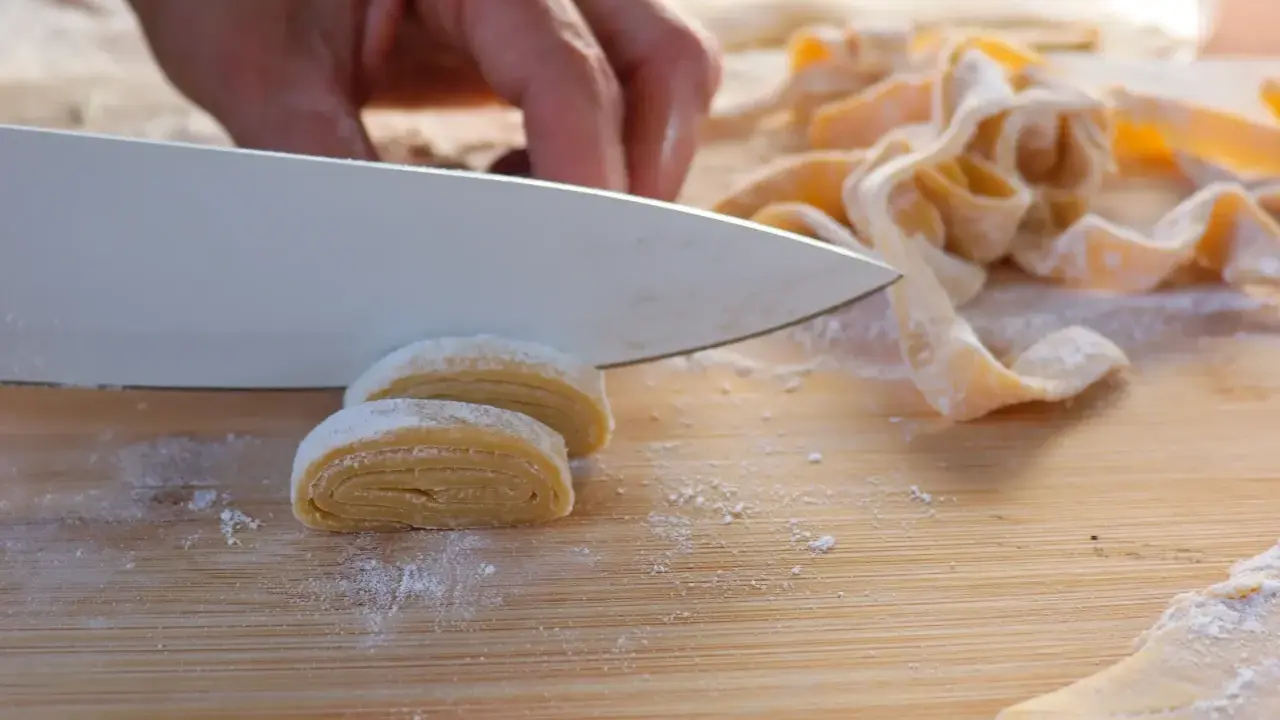 Frische Pasta wird mit einem Messer geschnitten. Der Teig muss ruhen, bevor er weiterverarbeitet wird.