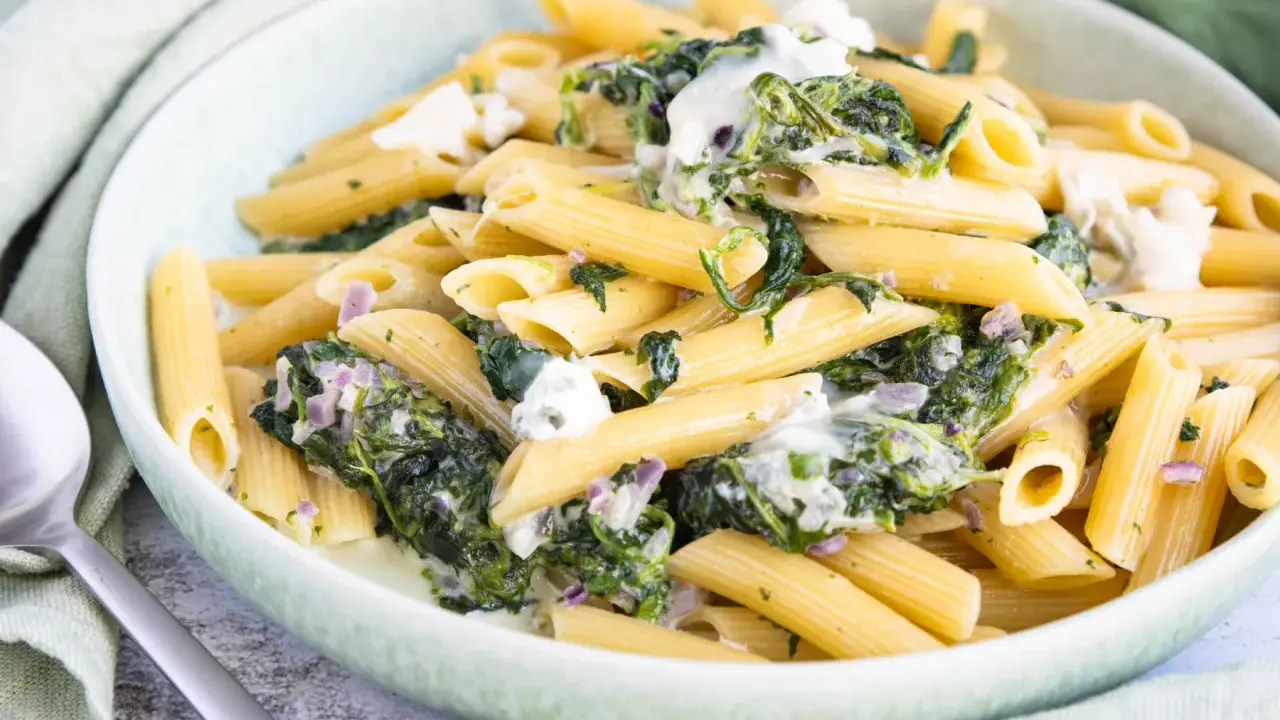 Penne-Nudeln mit cremiger Spinat-Gorgonzola-Sauce und zerbröckeltem Gorgonzola.