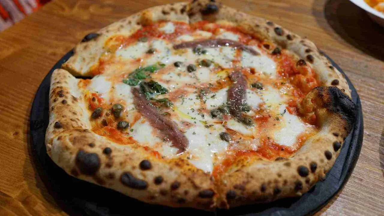 Eine original Pizza mit geschmolzenem Käse, Sardellen, Kapern und Basilikum.