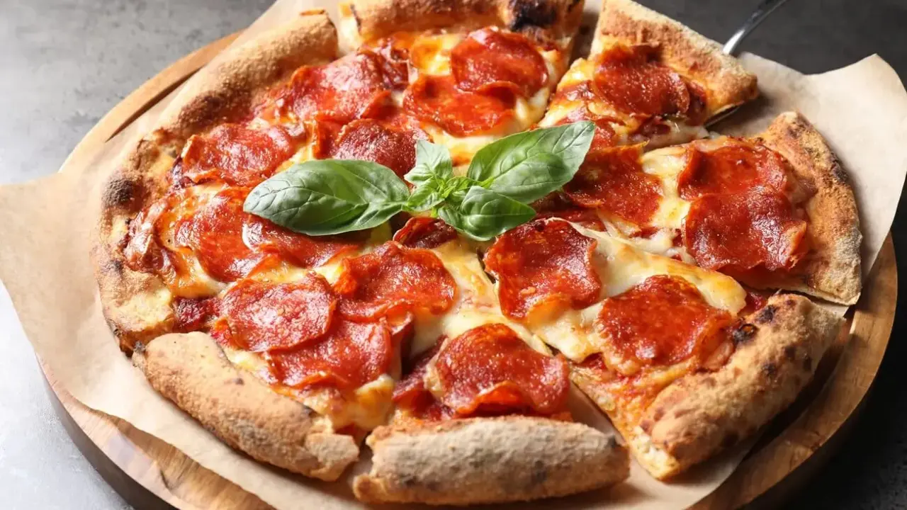 Eine köstliche Pizza mit geschmolzenem Käse und vielen Scheiben italienischer Salami, garniert mit frischem Basilikum.
