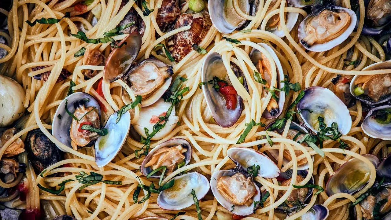 Spaghetti Vongole: Ein Teller voller goldener Spaghetti, vermischt mit frischen Venusmuscheln, Knoblauch und Kräutern.