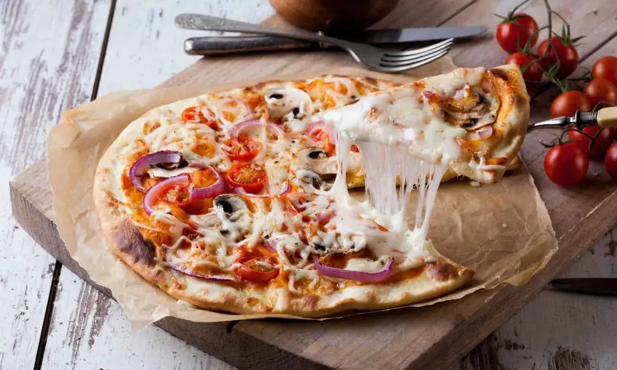 Perfekter Pizzateig Neapel, dank Thermomix! Eine dampfende Pizza mit geschmolzenem Käse, Tomaten und Pilzen wird serviert.