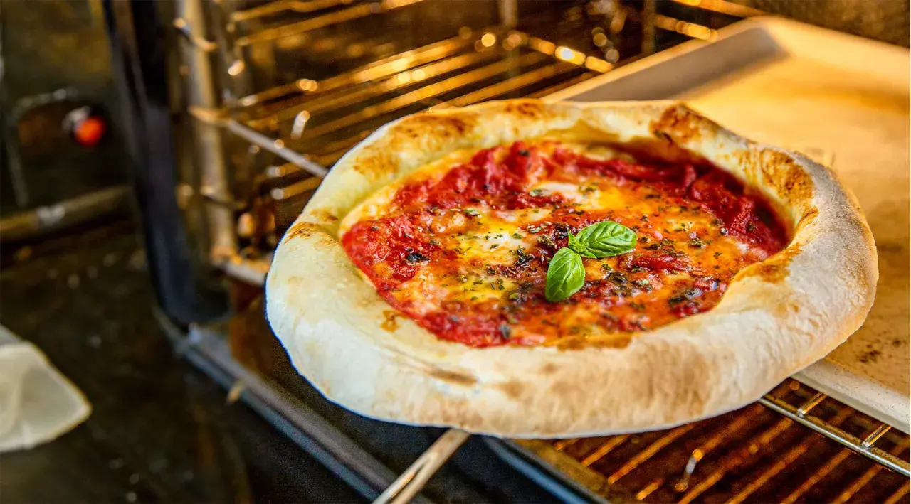 Frische Pizza Margherita mit geschmolzenem Käse und Basilikum wird im Ofen gebacken.