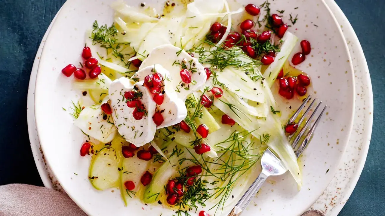Frischer Fenchel-Apfel-Salat mit Granatapfelkernen und Ziegenkäse, garniert mit Dill. Ein leichter Genuss.