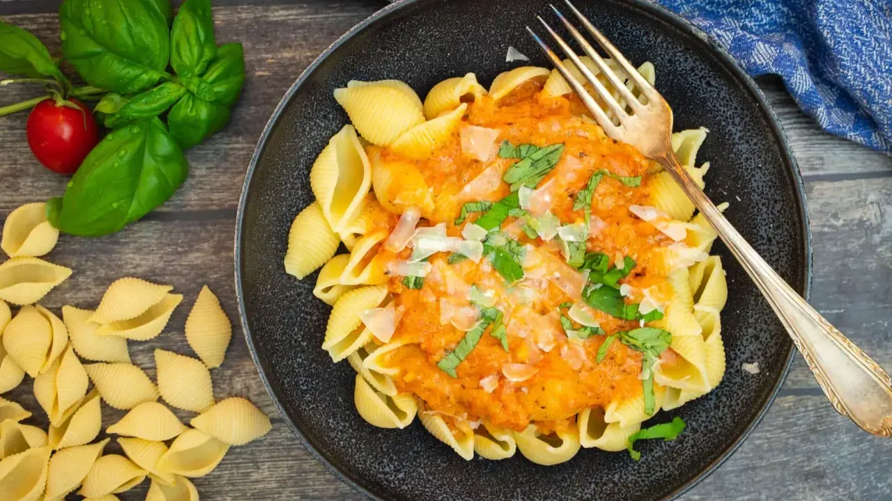 Herzhafte Muschelnudeln mit cremiger Tomaten-Sahne-Sauce, garniert mit frischem Basilikum und Parmesan. Ein Genuss!