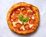 Eine köstliche New York Style Pizza mit Salami und frischem Basilikum, bereit zum Genießen.