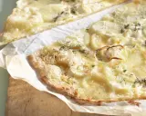 Dünne, knusprige knoblauch pizza mit geschmolzenem Käse und Zwiebelringen, garniert mit frischen Kräutern.