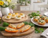 Leckere Vorspeise Ostern: Gefüllte Paprika, gefüllte Eier und herzhafte Törtchen auf einem Holztisch, dekoriert mit Kräutern und Osterhasen.