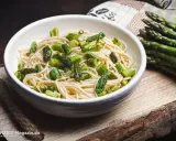 Eine Schüssel mit Spaghetti und frischem Spargel, dane liegt ein Bund grüner Spargel. Ein köstliches Gericht, das Lust auf mehr macht.