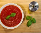 Schüssel mit cremiger Tomatensauce, garniert mit Basilikum. Daneben ein Glas Olivenöl und frische Basilikumblätter. Perfekt für Pasta mit San Marzano Tomaten.