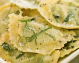 Mezzaluna pasta, gefüllt und mit Kräutern und Parmesan bestreut, liegt appetitlich in einer Schale.