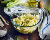 Frischer Fenchel Salat in einer Glasschüssel, garniert mit Dill. Daneben liegen Löffel und eine kleine Schale mit Salz.