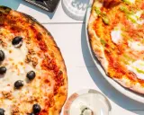 Zwei Pizzen, eine mit Thunfisch und Oliven, die andere mit Pesto. Das Geheimnis einer perfekten Pizza liegt oft im Mehl Typ 00.