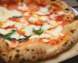 Ein frisch gebackener, italienischer Pizzateig mit geschmolzenem Mozzarella, Tomatensauce und Basilikum.