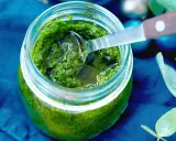 Frisches Rucola Pesto in einem Glas, bereit zum Genießen. Eine Löffelspitze ragt heraus.