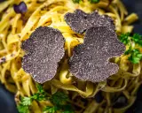 Feine Tagliatelle mit frischen Trüffelscheiben garniert. Ein luxuriöses Gericht, das die Aromen von Trüffel und Pasta vereint.