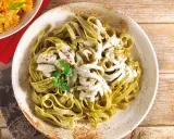 Grüne Bandnudeln mit cremiger Gorgonzola-Sauce, garniert mit Petersilie und roten Pfefferflocken.