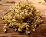 Ein Haufen ungekochte Pasta aus Hartweizengrieß (semola) liegt auf einem Holzbrett.