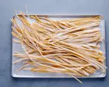 Frische, selbstgemachte Tagliatelle liegen auf einem Blech, bereit zum Kochen. Das Ergebnis von Tagliatelle selber machen.