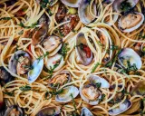 Spaghetti Vongole: Ein Teller voller goldener Spaghetti, vermischt mit frischen Venusmuscheln, Knoblauch und Kräutern.