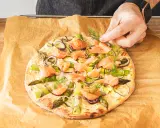 Eine köstliche Pizza mit Lachs, Spargel und roten Zwiebeln wird mit frischem Dill garniert.
