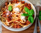 Eine Schüssel mit Linguine und einer herzhaften, **schnellen Bolognese**. Garniert mit frischem Basilikum und Parmesan.