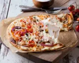Perfekter Pizzateig Neapel, dank Thermomix! Eine dampfende Pizza mit geschmolzenem Käse, Tomaten und Pilzen wird serviert.