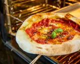 Frische Pizza Margherita mit geschmolzenem Käse und Basilikum wird im Ofen gebacken.