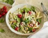 Pasta Primavera mit Penne, Brokkoli, Kirschtomaten, Spargel und Parmesan. Frisches Basilikum garniert dieses köstliche Gericht.
