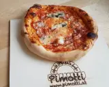 Eine knusprige Pancetta Pizza mit geschmolzenem Käse und Tomatensauce auf einem Holzbrett.