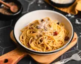 Eine Schüssel cremiger Spaghetti Carbonara, bestreut mit Parmesan und schwarzem Pfeffer, bereit zum Genießen.