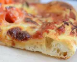 Ein Stück Pizza mit luftigem pizzateig, frisch aus dem pizzaofen. Der Teig ist goldbraun gebacken, die Tomatensoße und der Käse sind perfekt geschmolzen.