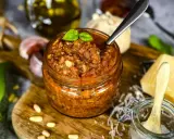 Ein Glas mit rustikalem Balsamico Pesto, garniert mit Basilikum. Daneben Pinienkerne, Knoblauch und Parmesan.
