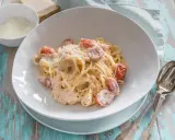 Cremige Pasta al Salmone mit Kirschtomaten und Parmesan, serviert auf einem rustikalen Holztisch.
