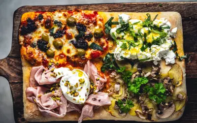 Vier verschiedene Beläge auf einer rechteckigen Pizza in Teglia: Oliven & Tomaten, Ricotta & Kräuter, Mortadella & Burrata, Kartoffeln & Pilze.