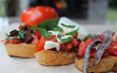 Drei italienische Bruschetta mit Tomaten, Mozzarella und Sardellen auf geröstetem Brot.
