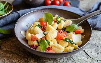 Ein köstlicher Gnocchi Salat mit Kirschtomaten, getrockneten Tomaten, frischem Basilikum und Parmesan.