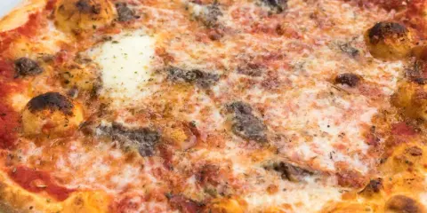 Eine knusprige Pizza Romana mit geschmolzenem Käse, Tomatensauce und dunklen, würzigen Belägen. Was ist drauf?