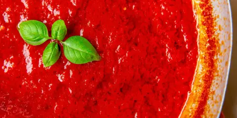 San Marzano Tomatensoße, perfekt für jedes Rezept. Ein Hauch frisches Basilikum rundet das Bild ab.