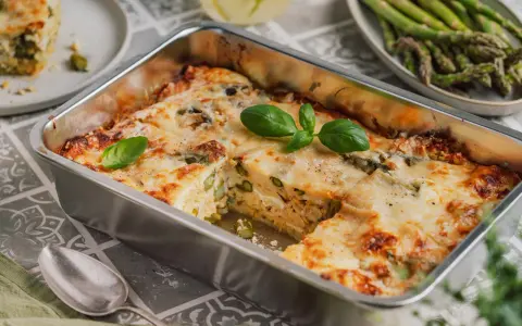 Herzhafte Spargel Lasagne mit geschmolzenem Käse, garniert mit frischem Basilikum. Ein Genuss für jeden Gaumen.