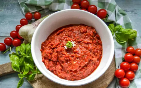 Frische tomaten pizza sauce, mit Basilikum und Knoblauch, umgeben von reifen Kirschtomaten.